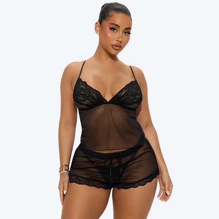 Model poses in a sexy black lace and sheer mesh sleepwear set with a cami and shorts, showcasing the new lingerie collection.