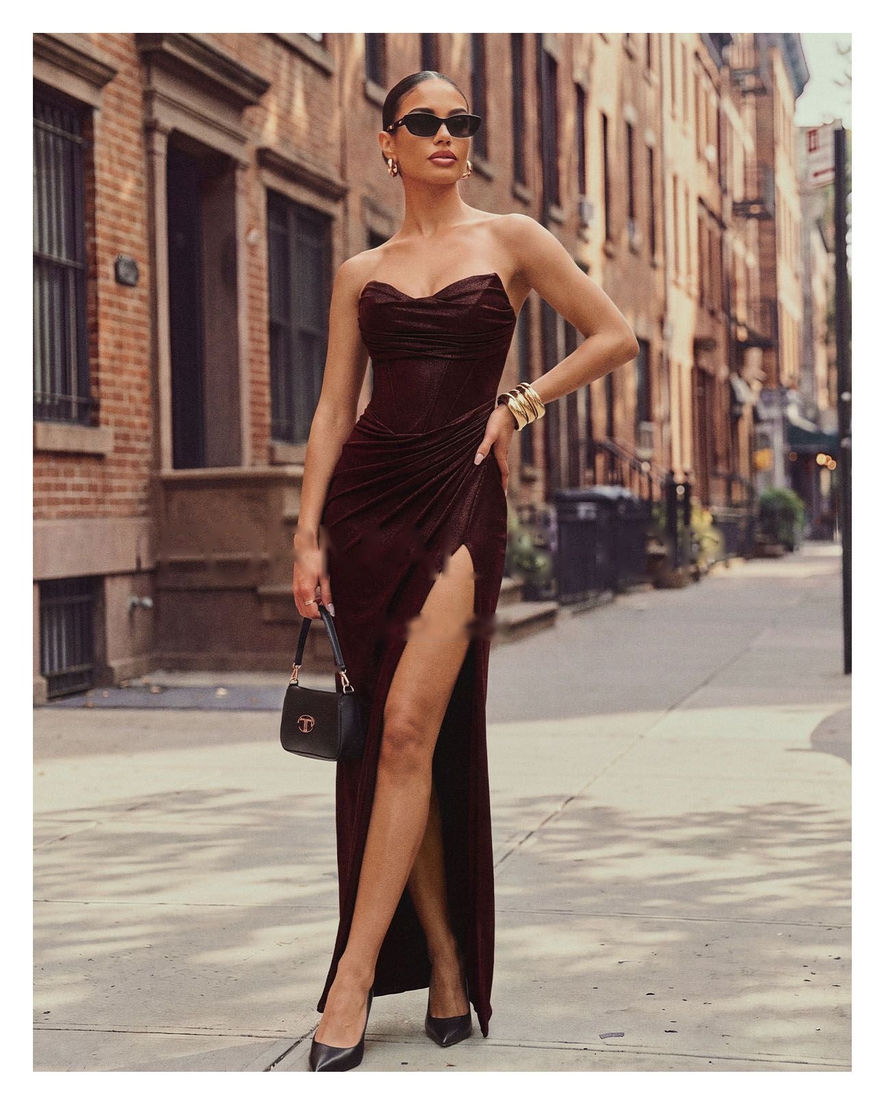 Femme en robe bustier bordeaux fendue dans une rue, pour la sélection tenues de soirée.